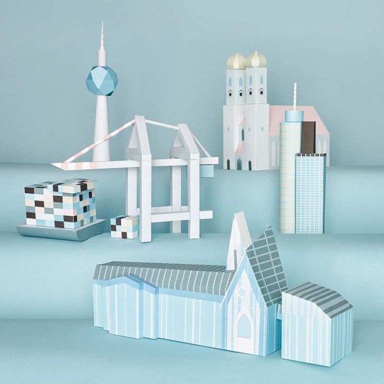 Paper Art für AD Magazin Bunte Papiermodell-Stadtlandschaft mit verschiedenen Gebäuden und Türmen auf blauem Hintergrund.